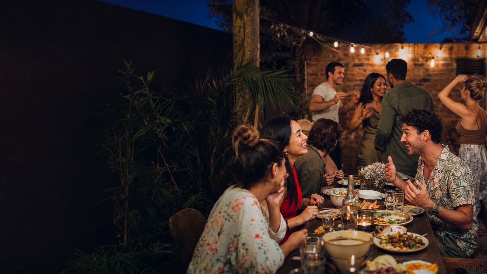 A lively group sharing dinner and conversation in a Sydney courtyard at dusk