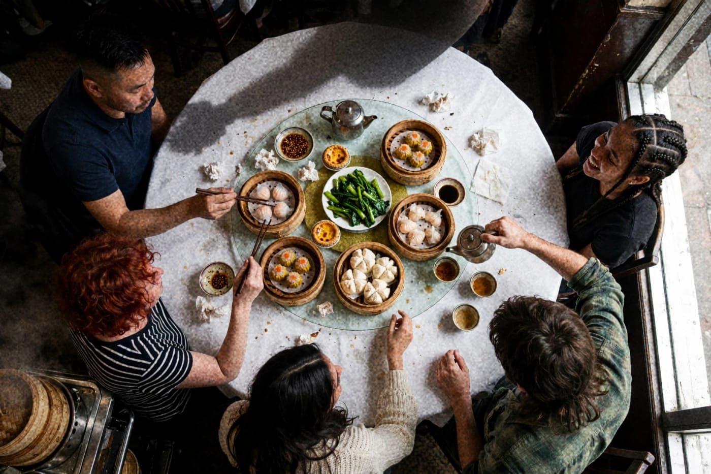 Friends sharing yum cha around a crowded lazy Susan, seen from above